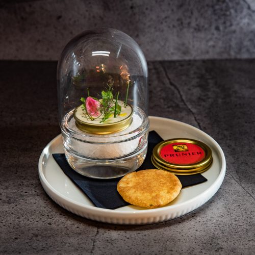 Caviarshot von Prunier mit Creme fraiche Haube und Kräutern unter einer Glasglocke mit Blini
